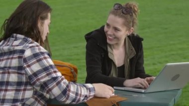 Parktaki iki genç proje üzerinde birlikte çalışıyor.