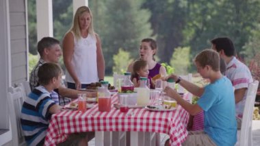 Bir grup insan arka bahçede barbekü yiyor ve eğleniyor.