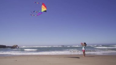 Kumsalda uçurtma uçuran genç kız.