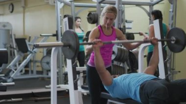 Spor salonundaki kadın ve erkek ağırlık kaldırıyor.