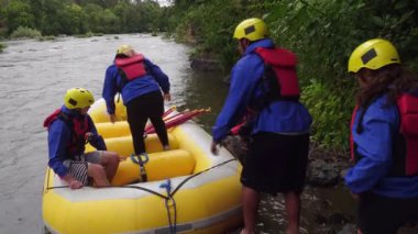 Rafting yapan bir grup insan sala biniyor.