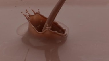 Çikolatalı süt yavaş çekimde akıyor ve sıçrıyor.