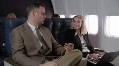 Uçuş görevlisi uçaktaki yolcularla konuşuyor.