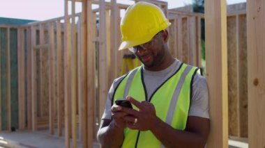 İnşaat işçisi cep telefonundan mesaj atıyor.