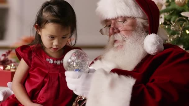 Święty Mikołaj Pokazuje Małej Dziewczynce Kulę Śnieżną — Wideo stockowe