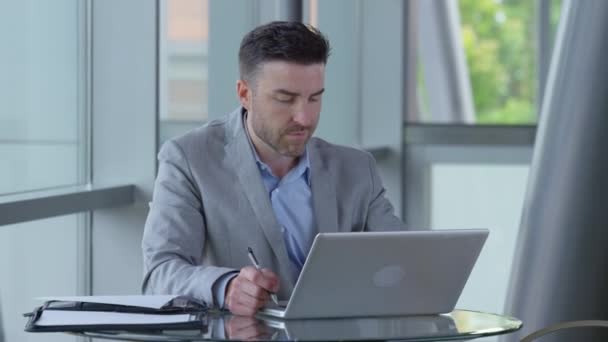 オフィスのロビーでラップトップコンピュータを使用して若いビジネスマン — ストック動画
