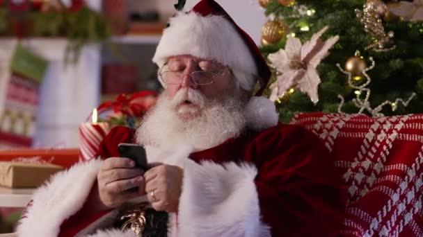 サンタクロースは携帯電話でテキストメッセージを送信し セルフィーを取る — ストック動画