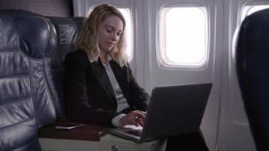 Uçakta dizüstü bilgisayar kullanan iş kadını
