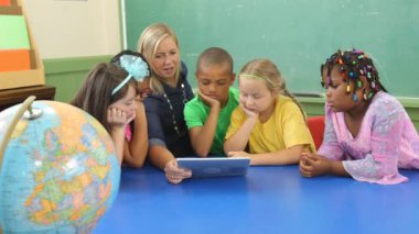 Öğretmen ve öğrenciler dijital tablet üzerinde çalışıyorlar