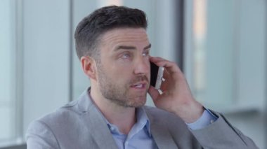 Genç işadamı ofis lobisinde cep telefonu kullanıyor.