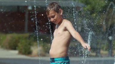 Su çeşmesinde oynayan genç bir çocuk, süper yavaş çekim.