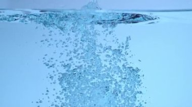 Su altında su sıçrıyor ve ağır çekimde kabarcıklar oluşuyor.