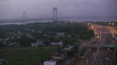 New York şehri 2017 dolaylarında, gişeden geçip Verrazano-Narrows Köprüsü 'ne doğru uçuyor. Cineflex ve RED Epic-W Helyum ile çekilmiştir..