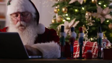 Noel Baba atölyede dizüstü bilgisayar kullanıyor.