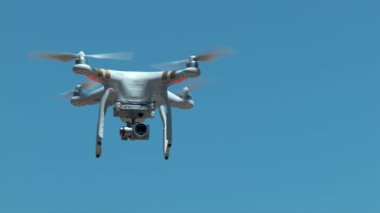 Mavi gökyüzüne karşı ağır çekimde uçan drone.