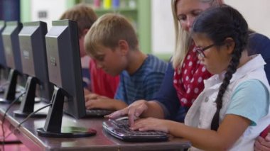 Öğretmen ve öğrenci okulda bilgisayar üzerinde çalışıyorlar.
