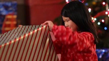 Genç kız yılbaşı hediyesini yırtıyor.