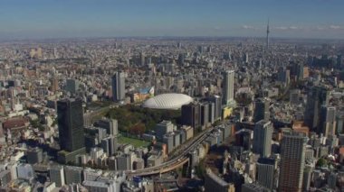 Tokyo, Japonya 2018 dolaylarında. Skytree uzaktayken Tokyo Dome 'a doğru uçuyor. Kırmızı kamerayla helikopterden çekilmiş..