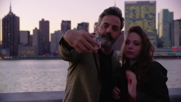 ニューヨークのカップルは 背景に都市のスカイラインと携帯電話の自撮りを取ります — ストック動画