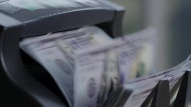 100 dolarlık banknotlarla para sayma makinesinin yakın plan çekimi..