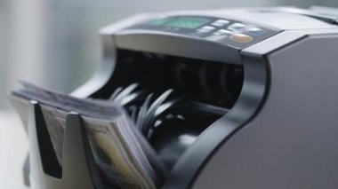 100 dolarlık banknotlarla para sayma makinesinin yakın plan çekimi..