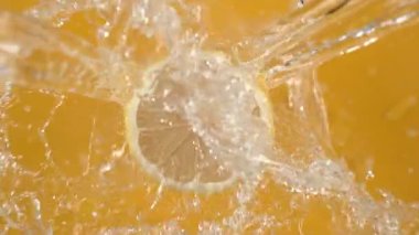Sarı arka planda limondan akan su. Fantom Flex 4K kamerayla ağır çekimde çekildi..