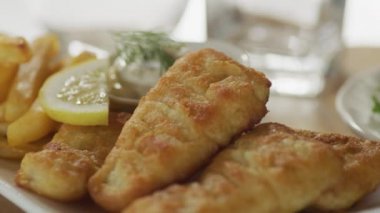 Tabakta balık ve patates kızartması, garnitür ve limon..
