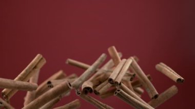 Tarçın çubukları kırmızı arka planda yavaş çekimde uçuyor. Phantom Flex 4K kamera ile çekildi..