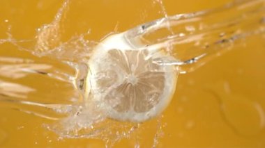 Sarı arka planda limondan akan su. Fantom Flex 4K kamerayla ağır çekimde çekildi..