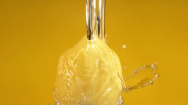 Sarı arka planda limondan akan su. Fantom Flex 4K kamerayla ağır çekimde çekildi..