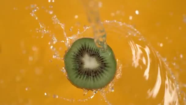 Agua Girando Fuera Kiwi Sobre Fondo Amarillo Grabado Cámara Lenta — Vídeo de stock