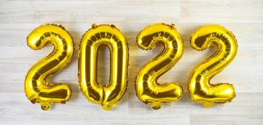 Altın helyum balonları ahşap zemin üzerinde 2022 rakamları. Mutlu yıllar konsepti. Selamlar ve davetiyeler. Düz yatış, üst görünüm
