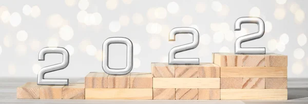 Wooden ladder with grey numbers 2022 and glittering bokeh. Concept of success, career climb, and development in the future new year. Banner — Stock Photo, Image