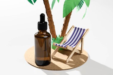 Kahverengi damlatan cam şişe ve beyaz arka planda palmiyenin altında şezlong. Güneş banyosu sırasında cilt bakımı. Organik mineral kozmetik ürünü. Model ol, vitrin