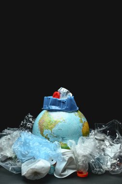 Siyah arka planda plastik çöplerle çevrili bir dünya küresi. Plastik ve polietilen ile Dünya kirliliği kavramı. Boşluğu kopyala