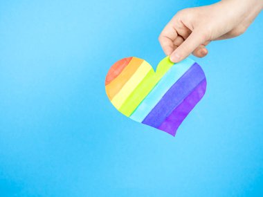 Mavi arka planda çok renkli kalbi tutan bir kadın. Aşk kavramı, LGBT