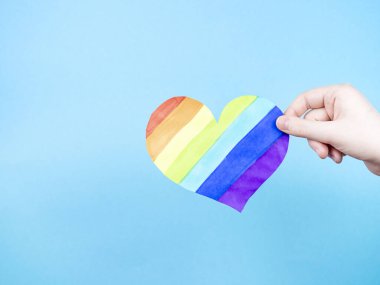 Mavi arka planda çok renkli kalbi tutan bir kadın. Aşk kavramı, LGBT