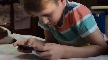 11 yaşında Avrupa görünümlü bir çocuk, evde telefonla oynuyor..