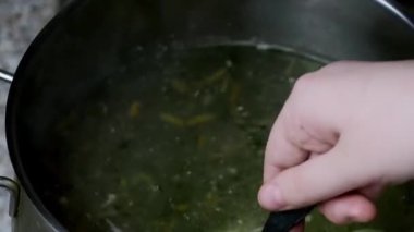 Çorba tencerede kaynamış, kaşıkla karıştırılmış. Ev yapımı yemek pişirme kavramı.