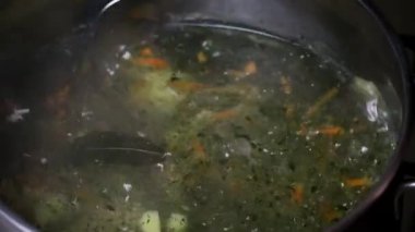 Çorba tencerede kaynamış, kaşıkla karıştırılmış. Ev yapımı yemek pişirme kavramı.