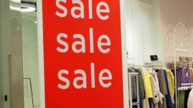 Giysi mağazasında büyük kırmızı bir pankart var. 