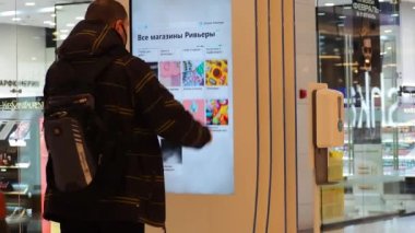 Alışveriş merkezindeki bir adam bilgi panosu kullanıyor. Rusya Moskova 22.02.2022