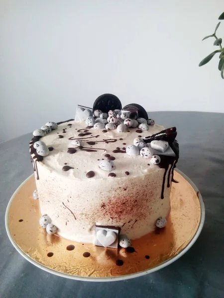 Svart och vit tårta med kakor, godis och choklad på grått bord — Stockfoto