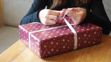 Kız Noel hediyesine fiyonk bağlıyor.