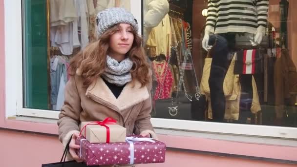 Adolescente segurando um conjunto de presentes de Natal perto da janela lojas — Vídeo de Stock