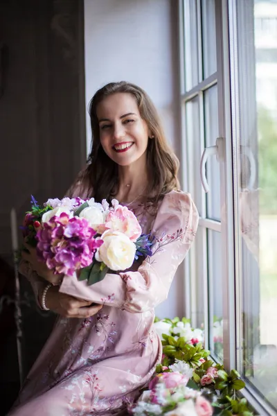 Frau mit braunen Haaren und roten Lippen, bekleidet mit einem rosa Kleid — Stockfoto