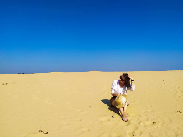 Молодая женщина в белой блузке и коричневых шортах ходит по пустыне