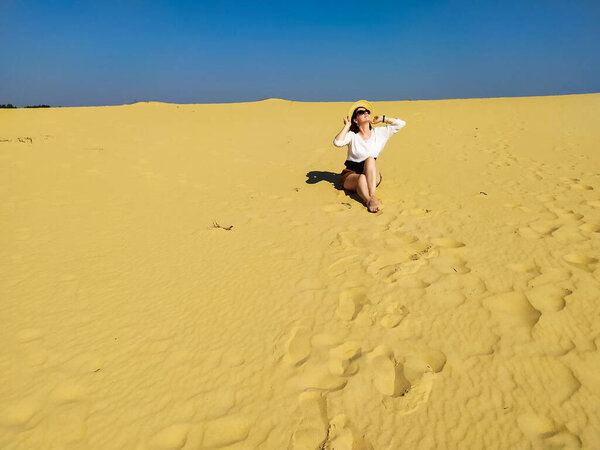 Молодая женщина в белой блузке и коричневых шортах ходит по пустыне
