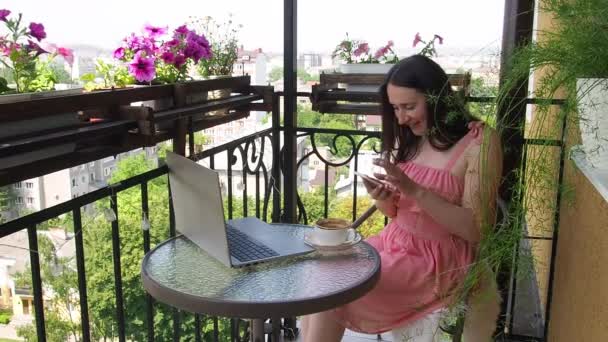 Femeia care folosește laptop și smartphone pe balcon — Videoclip de stoc