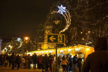 Debrecen, Macaristan - Aralık 2021: Eski Kossuth Meydanı 'ndaki tarihi Macar kenti ve geceleri yürüyen insanlar. Debrecen 'in güzel şehir merkezi ve pazar için ahşap kulübeler